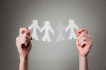 A paper cutout of people holding hands together, representing community