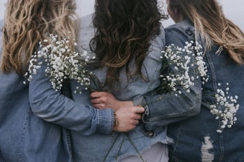 Group of women facing backward with flowers in hand 