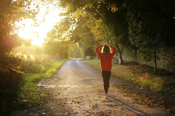 woman walking on path in sunlight