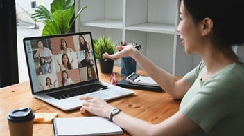 young asian woman talking to colleagues on computer