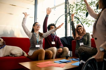 a group of people raising their hands and laughing on couch 