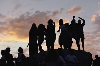 A silhouette of a group of people standing on a rock 