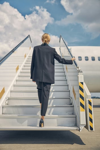 woman in suit walking up airplane 