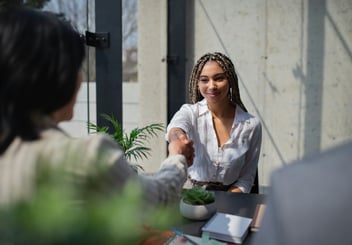 woman shaking her hand with another professional during a meeting 