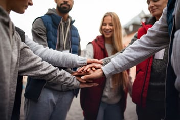 a group of people gathering hands in middle 