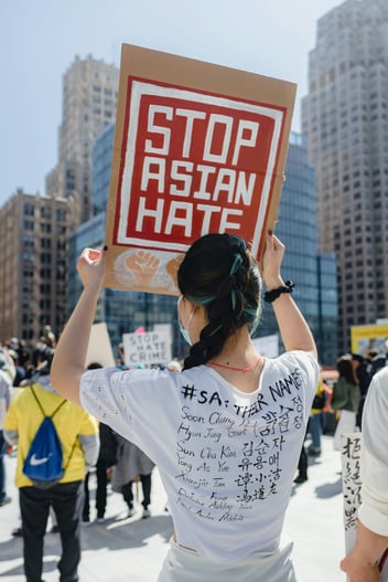 woman holding up stop asian hate sign during demonstration