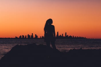 A woman standing in front of a city during dusk 