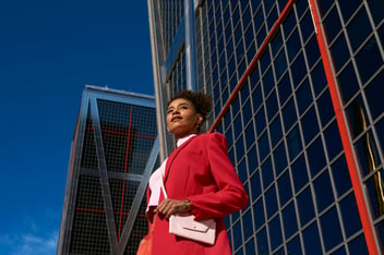 woman in red suit posing in front of skyscraper