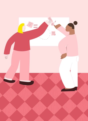 two women pointing at a board