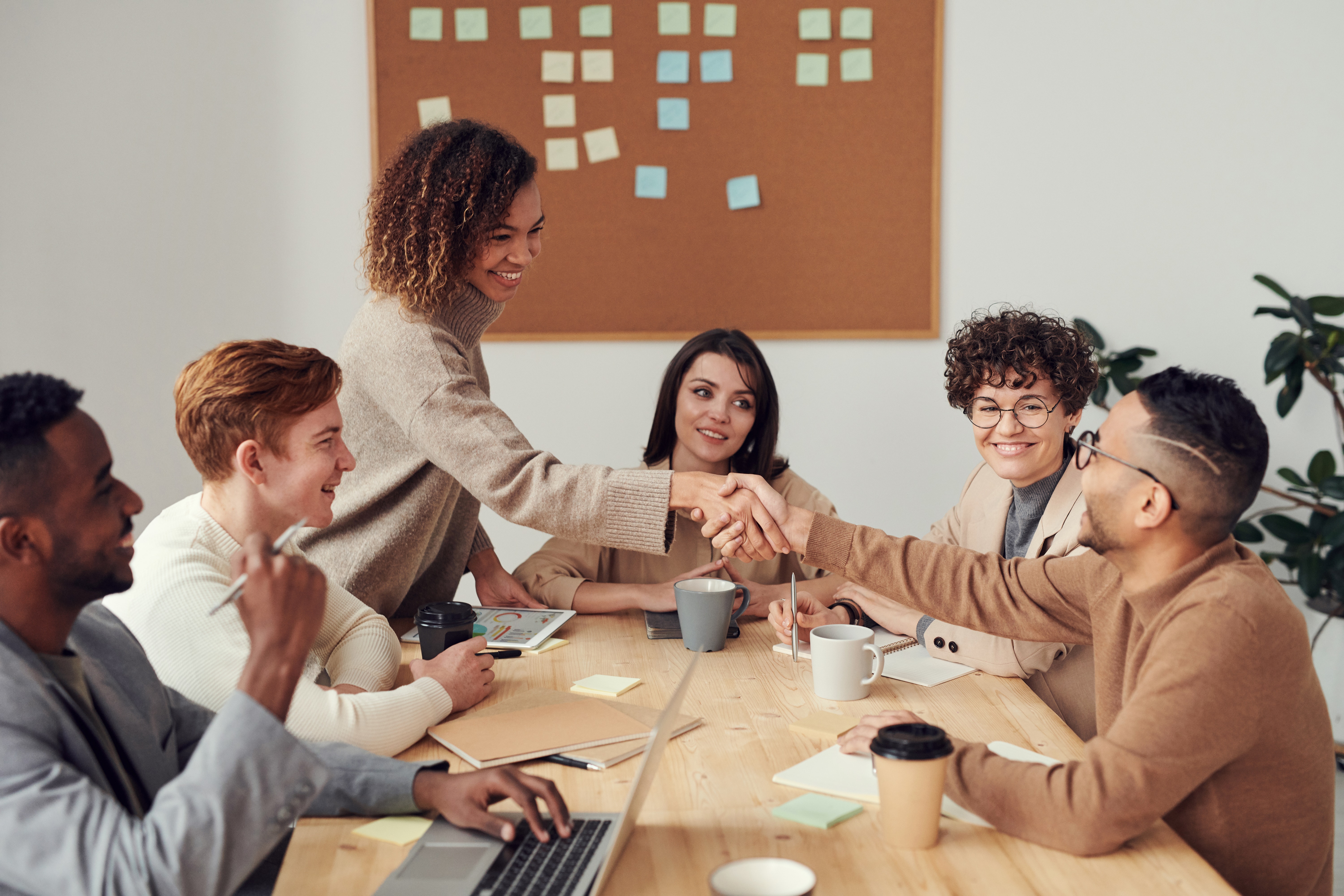 Team shaking hands at the boardroom table.