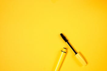 Yellow mascara against a yellow background.