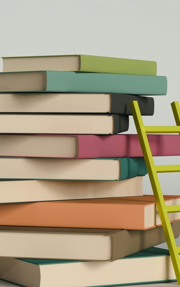 a stack of multicolored books and a ladder resting on the side of the covers