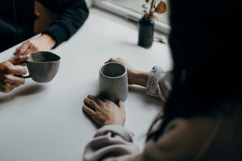 two people sitting with mugs