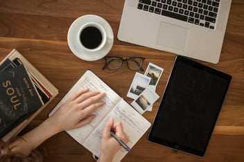 Person holding ball point pen writing in a notebook 